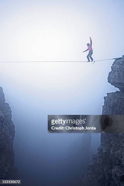 man balancing over high rope between two cliffs in mountains, tirol, austria - drahtseilakt stock-fotos und bilder