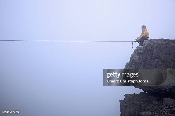 man sitting in front of high line between two rocks, tirol, austria - tightrope stock pictures, royalty-free photos & images