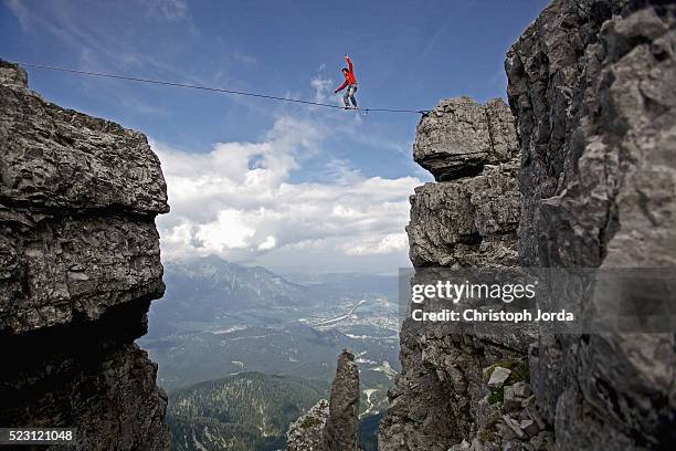 young man balancing on high rope between two rocks in mountains, alps, tyrol, austria - tightrope walker stock pictures, royalty-free photos & images