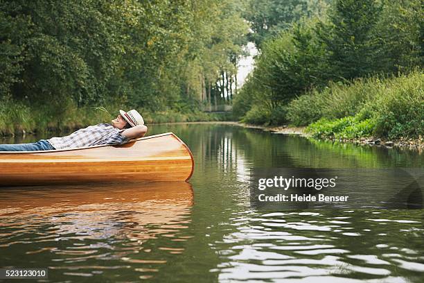 man resting in a canoe - canoe stock-fotos und bilder