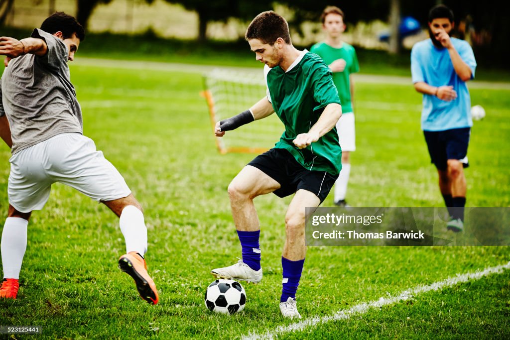 Two male soccer players battling for ball