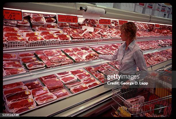 shopper selects meat in supermarket - meat stockfoto's en -beelden