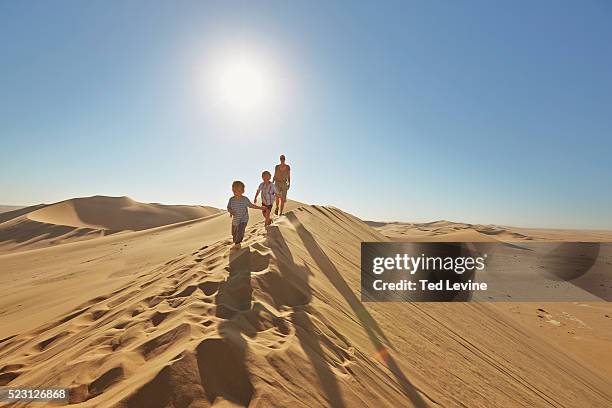 family walking up a sand dune - walvis bay stock-fotos und bilder