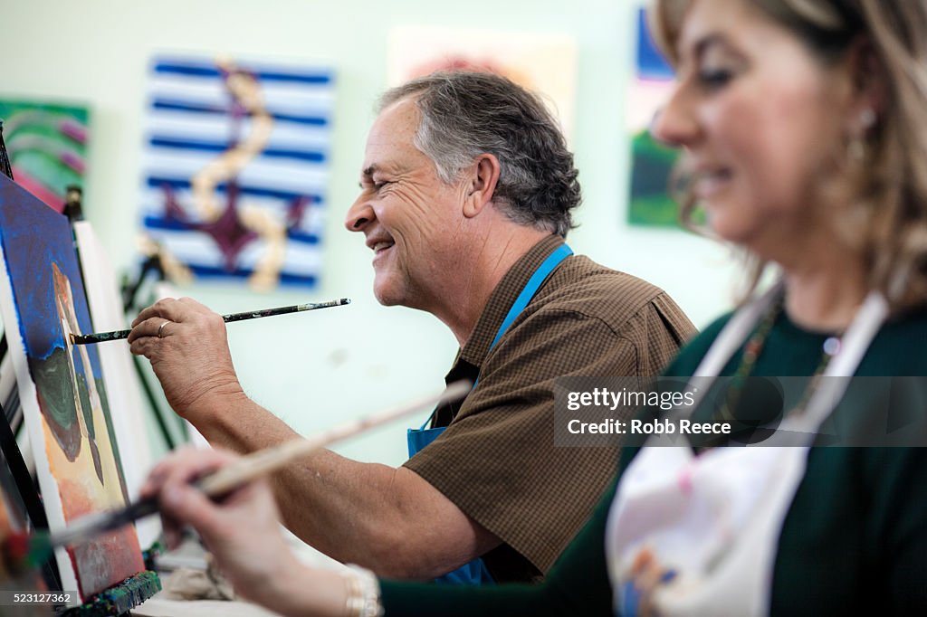 A man and woman painting fine art together in a studio