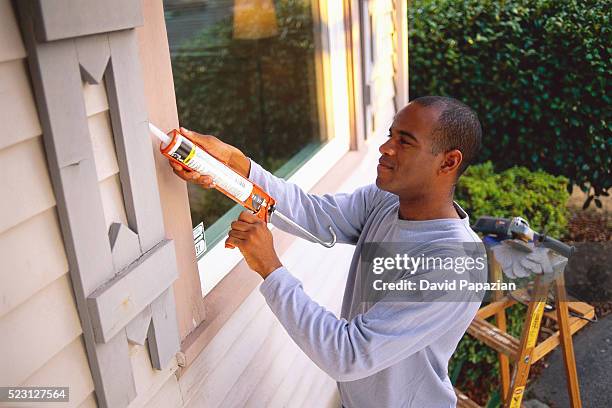 man using chemical on window - caulk stock pictures, royalty-free photos & images