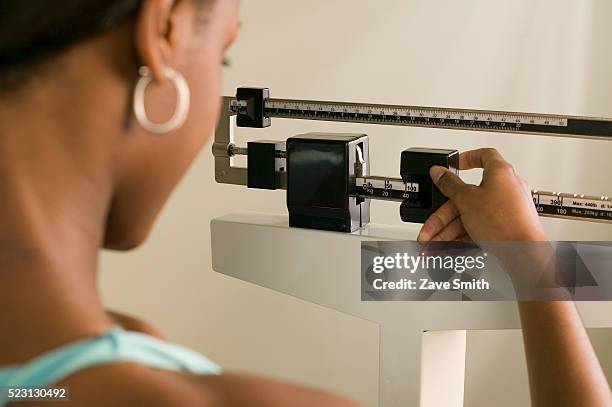woman weighing herself - preocupación por el cuerpo fotografías e imágenes de stock