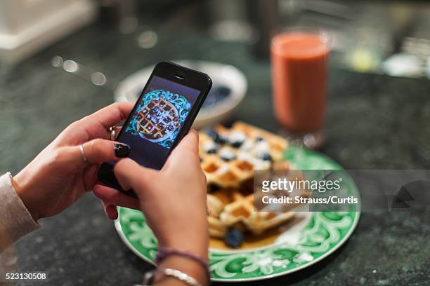 Hand using smartphone to take photo of breakfast
