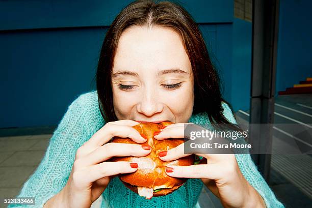 young woman eating burger - burger portrait stock-fotos und bilder