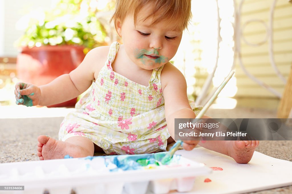 Baby (12-23 months) playing with paint outside