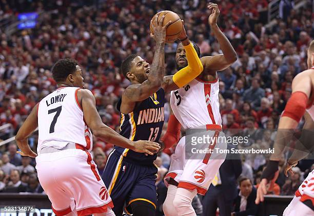 Paul George of the Indiana Pacers is fouled as he goes to the basket by DeMarre Carroll of the Toronto Raptors as Kyle Lowry also tries to defend in...
