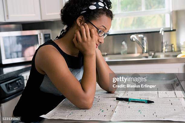 girl reading newspaper in kitchen - werkloos stockfoto's en -beelden