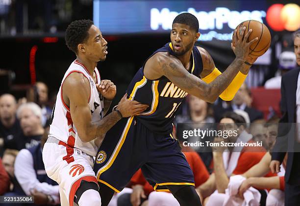 Paul George of the Indiana Pacers holds on to the ball as he is guarded by DeMar DeRozan of the Toronto Raptors in Game One of the Eastern Conference...