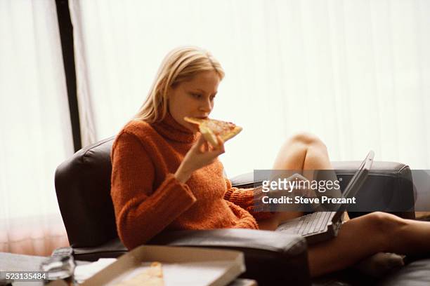 woman with laptop eating pizza - woman junk food eating stockfoto's en -beelden