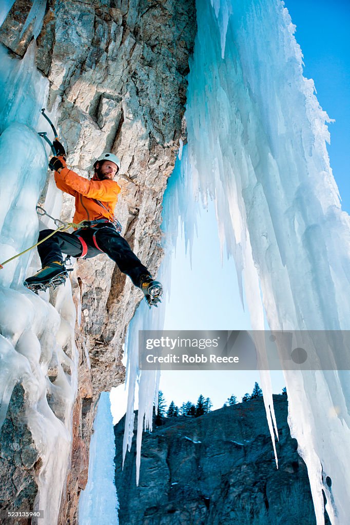 A man ice climbing on a frozen waterfall in Colorado