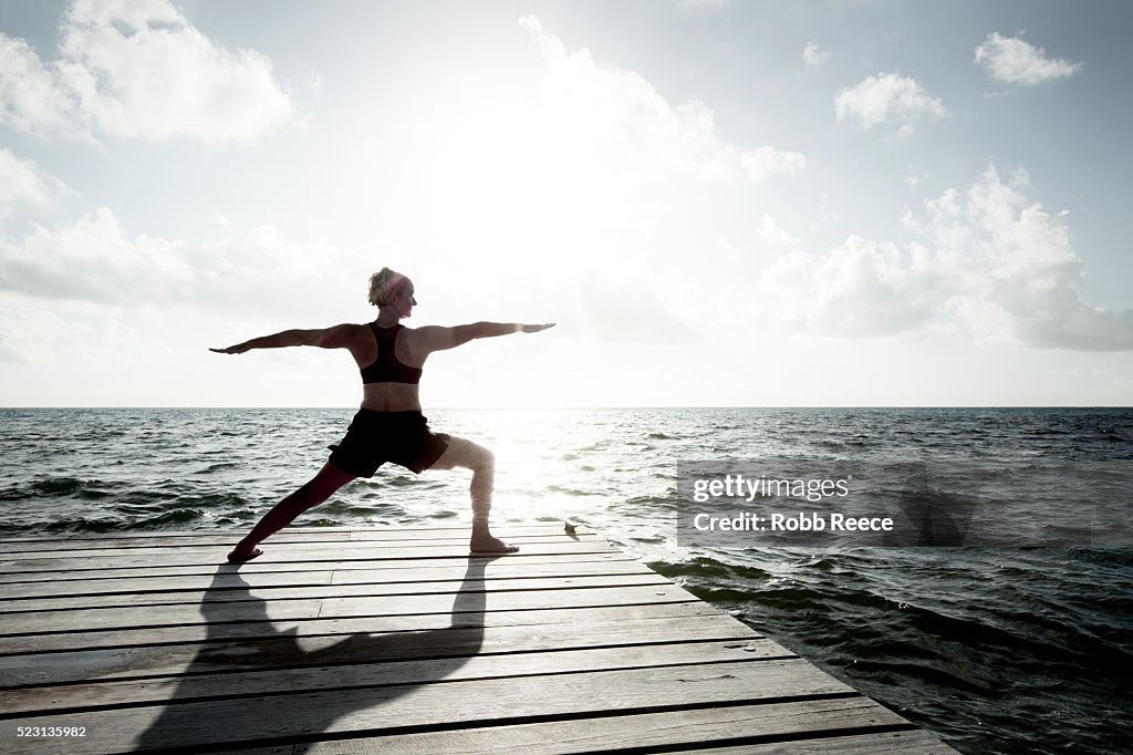A woman on vacation in Belize, practicing yoga on a dock near the Caribbean Ocean