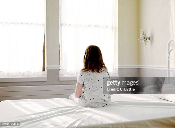 girl sitting on hospital bed - child in hospital stock-fotos und bilder