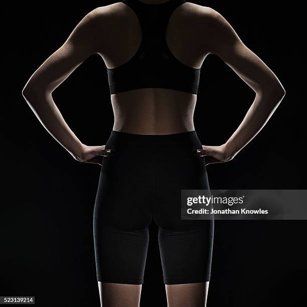 mid section rear view of female wearing gym sports clothing, studio shot against black background - body part black background stock pictures, royalty-free photos & images