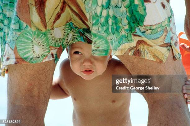 playing peek-a-boo under daddy's shorts - enfants plage photos et images de collection