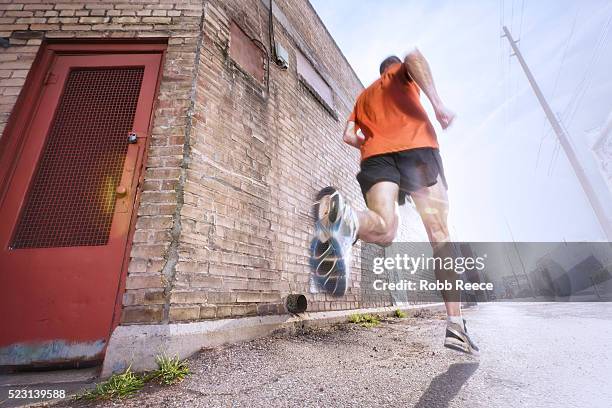 a man running on a city street for fitness - road running stock pictures, royalty-free photos & images
