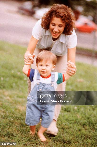 mother helping son take first steps - bib overalls stock pictures, royalty-free photos & images