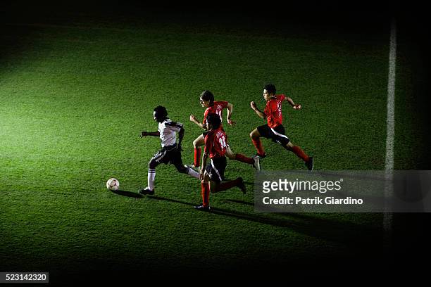 soccer players chasing ball - football player running stock pictures, royalty-free photos & images