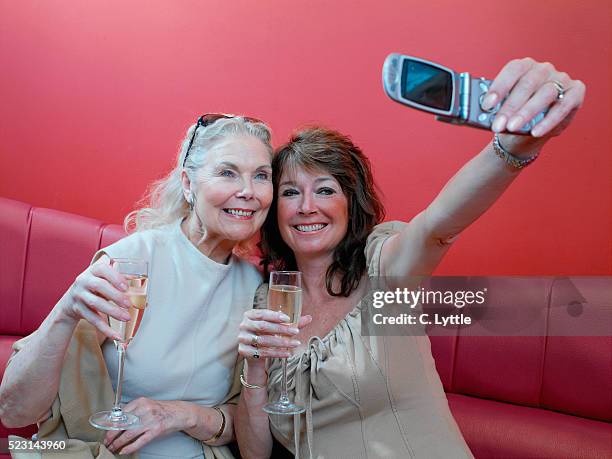 two women taking a picture with cell phone in a bar - champagne coloured stock-fotos und bilder