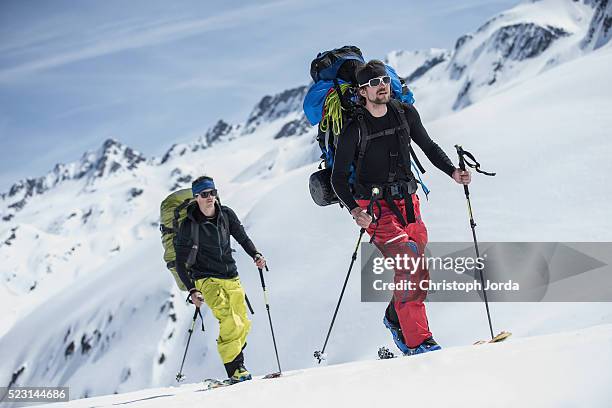 ski tourers hiking up a mountain - scialpinismo foto e immagini stock
