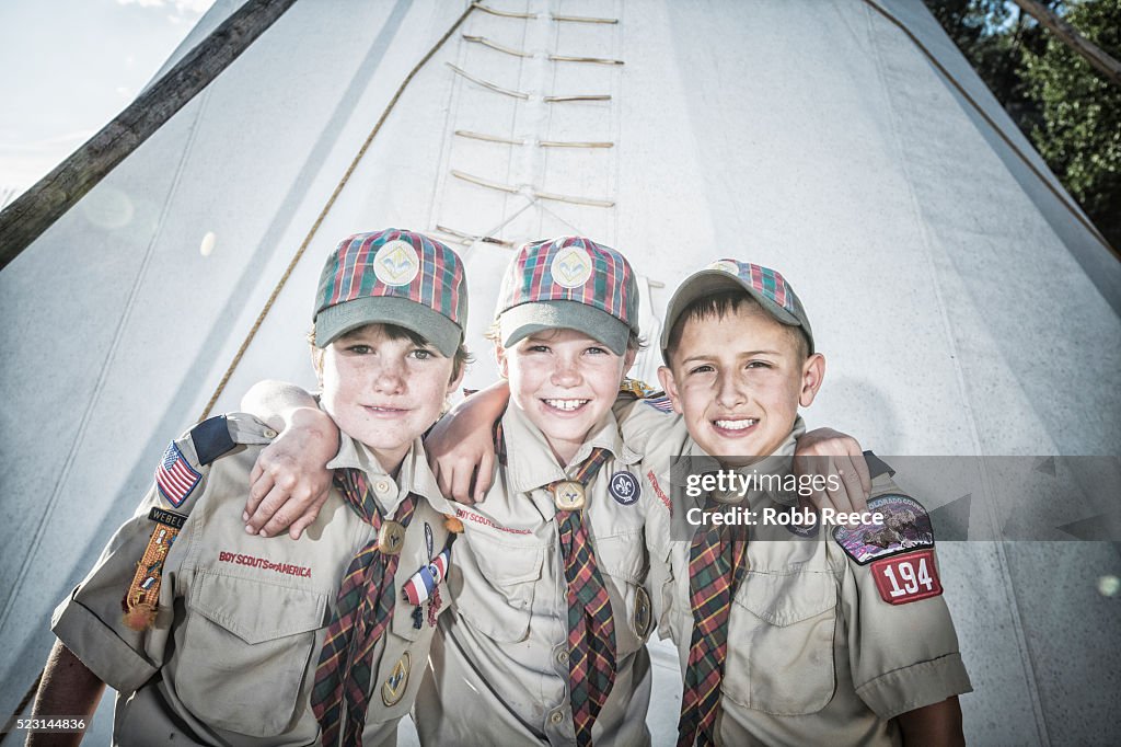 Three young, Weblo boy scout friends standing near a teepee at their camp in Colorado.