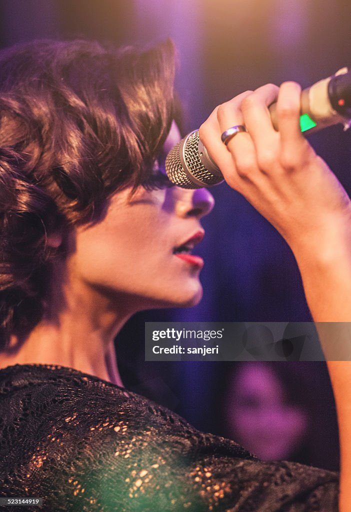 Beautiful woman during concert holding a microphone