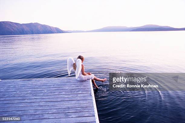 girl with angel wings splashing feet in lake - see through negligee stock-fotos und bilder