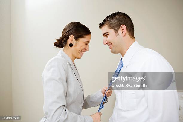 wife adjusting her husband's necktie - adjusting necktie stockfoto's en -beelden
