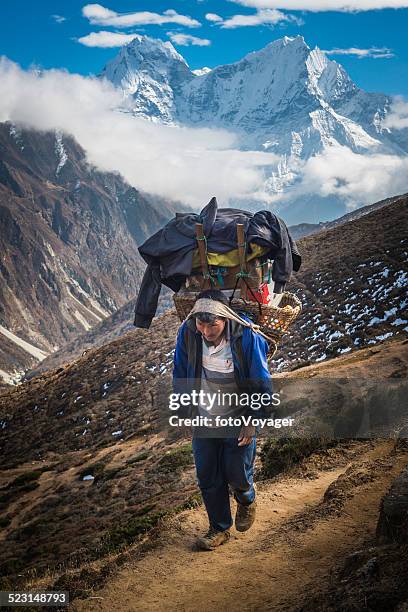 sherpa carrying traditional basket along himalaya mountain trail nepal - porter stock pictures, royalty-free photos & images