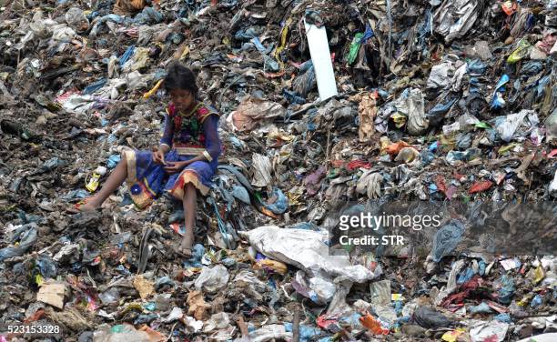 Young Indian child sits among piles of garbage at a dumping site in Dimapur on April 22 on World Earth Day. - Earth Day is observed each April 22,...