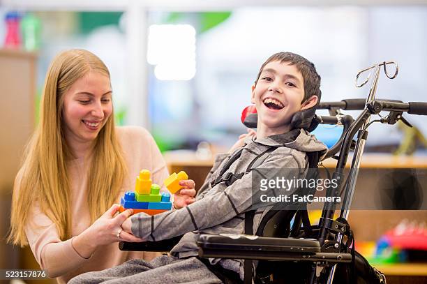 glückliche jungen spielen mit spielzeug - persons with disabilities stock-fotos und bilder
