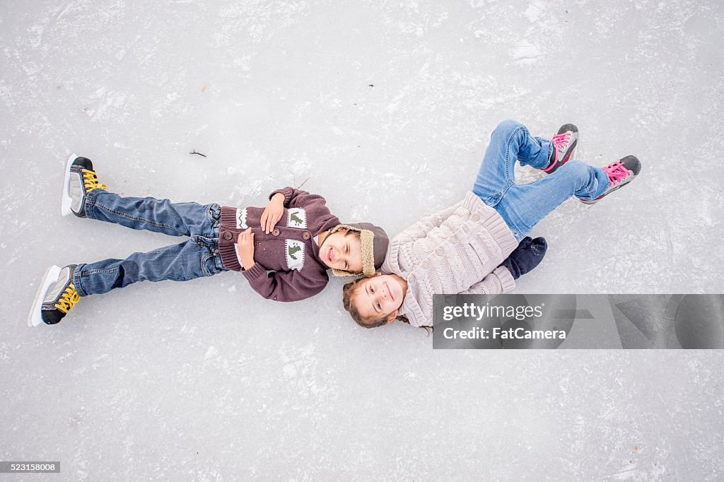 Bruder und Schwester liegend einem gefrorenen Teich