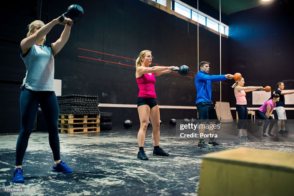 People training with kettle bells in fitness class