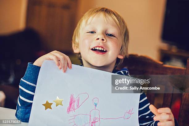 smiling child holding up a picture he has drawn - kids drawings stock pictures, royalty-free photos & images