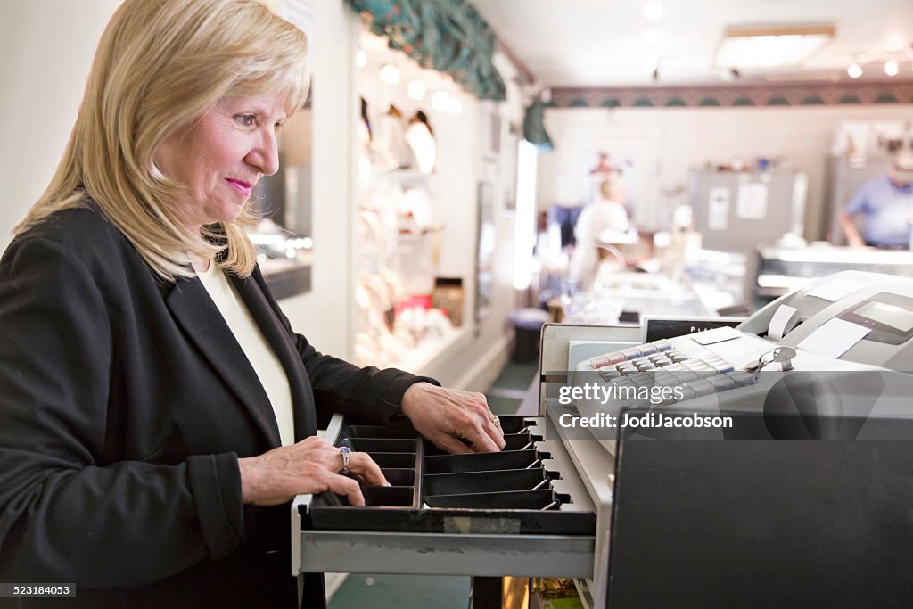 Caucasian woman store owner takes money from the cash register