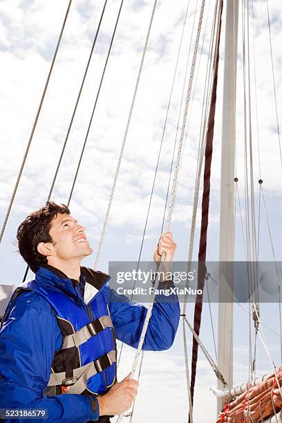 homem de elevação navegue no barco à vela - hastear - fotografias e filmes do acervo