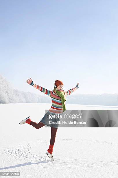 woman balancing on one ice skate - skate sports footwear stock-fotos und bilder
