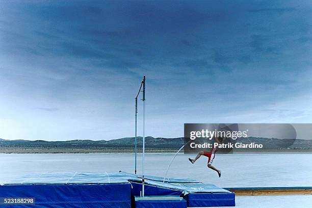 man pole vaulting in salt flat - stabhochsprung stock-fotos und bilder