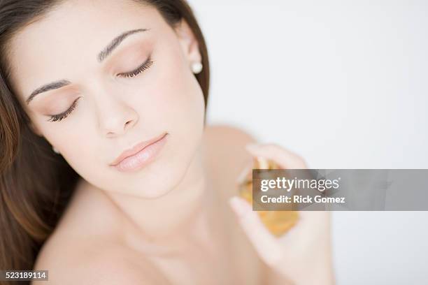 young woman spraying perfume - scented foto e immagini stock