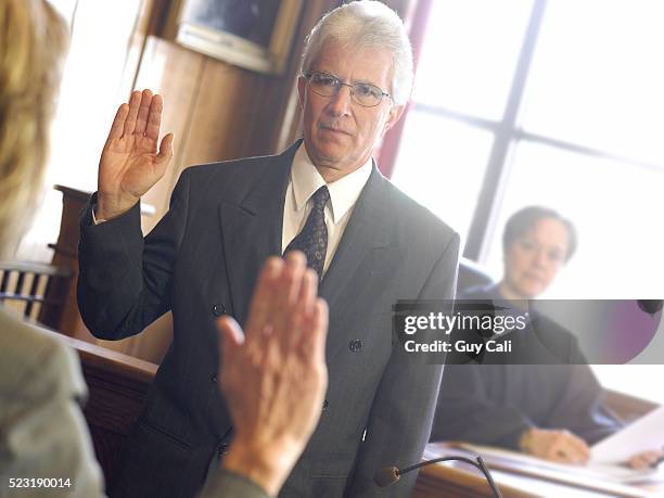 man in witness box swearing oath - giuramento foto e immagini stock