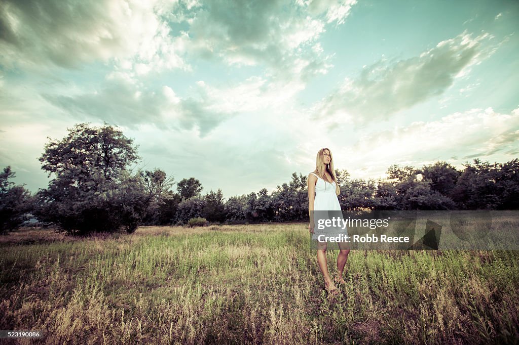 A beautiful woman standing in a field looking at the sky