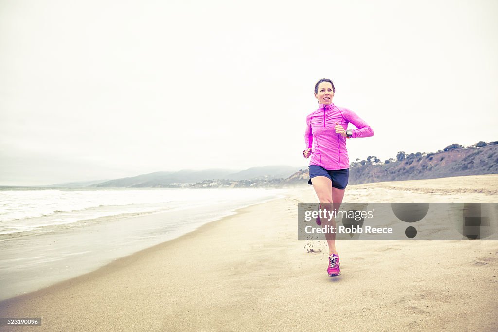 A fit woman running fast in the sand on the beach for fitness training