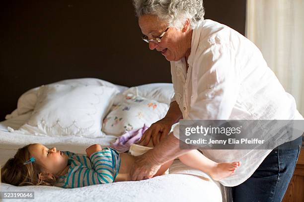 grandma changing granddaughter's (2-3) diaper on bed, california, usa - changing diaper photos et images de collection