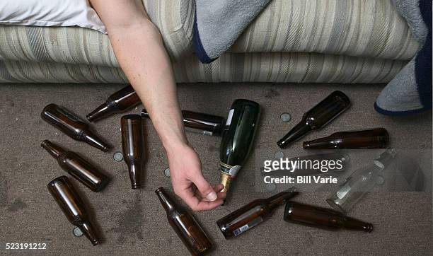 drunk man and beer bottles - alcolismo foto e immagini stock
