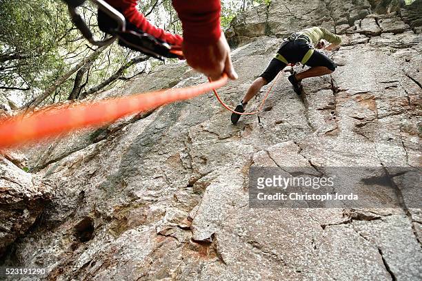 young man climbing on a rock - belaying stock pictures, royalty-free photos & images