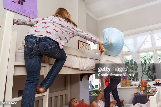 sisters (6-7, 10-12) having pillow fight in bedroom - bunk beds for 3 stock-fotos und bilder