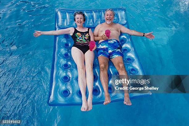 senior couple relaxing in pool - airbed stock pictures, royalty-free photos & images